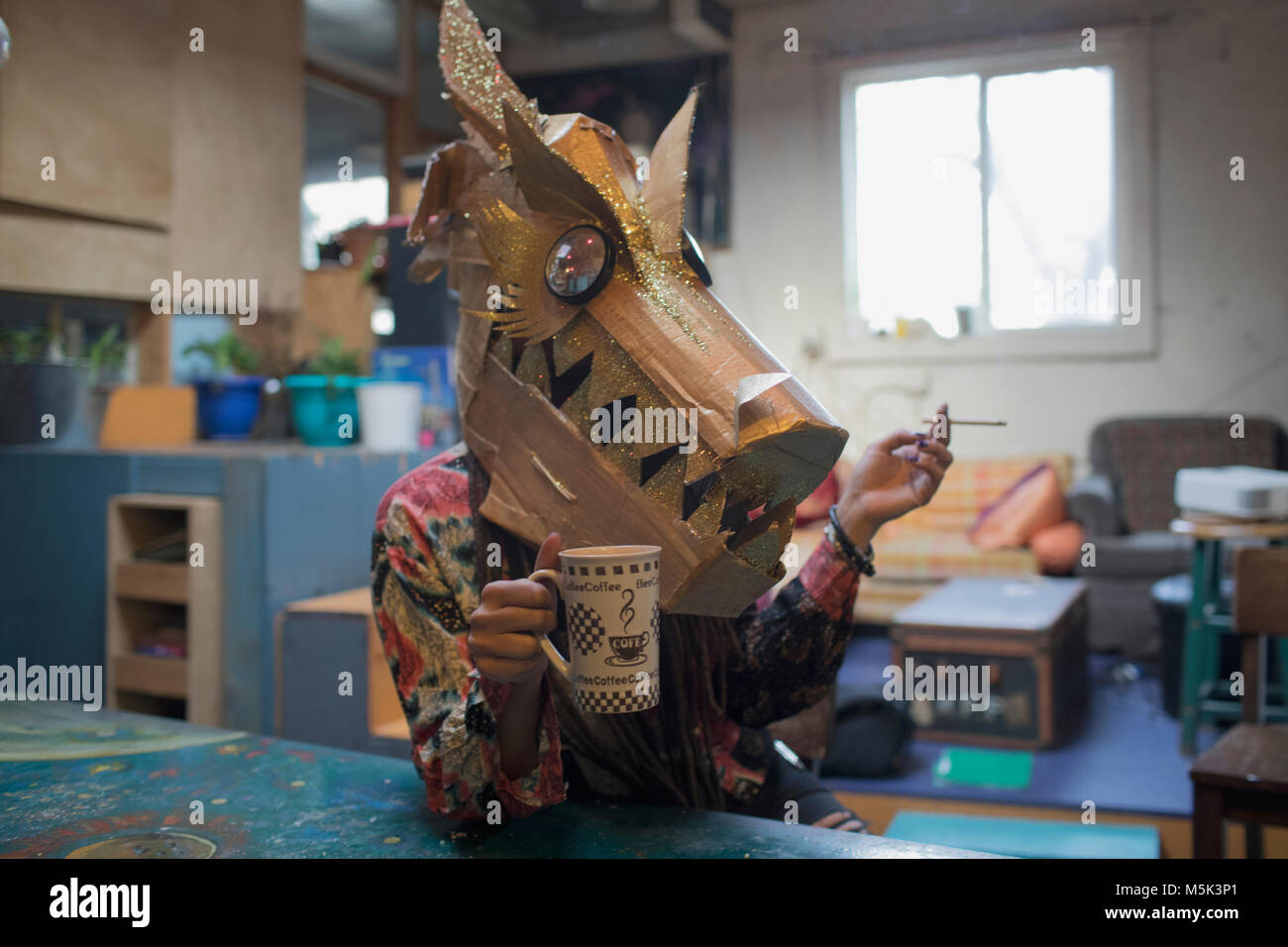 Portrait of young female artist wearing a dragon mask Stock Photo