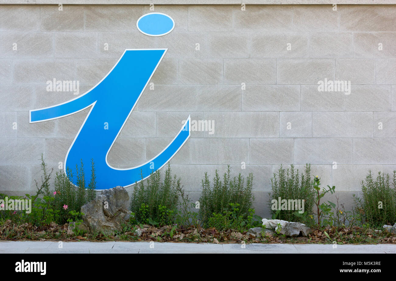 Blue information sign on the exterior wall over a flowerbed Stock Photo