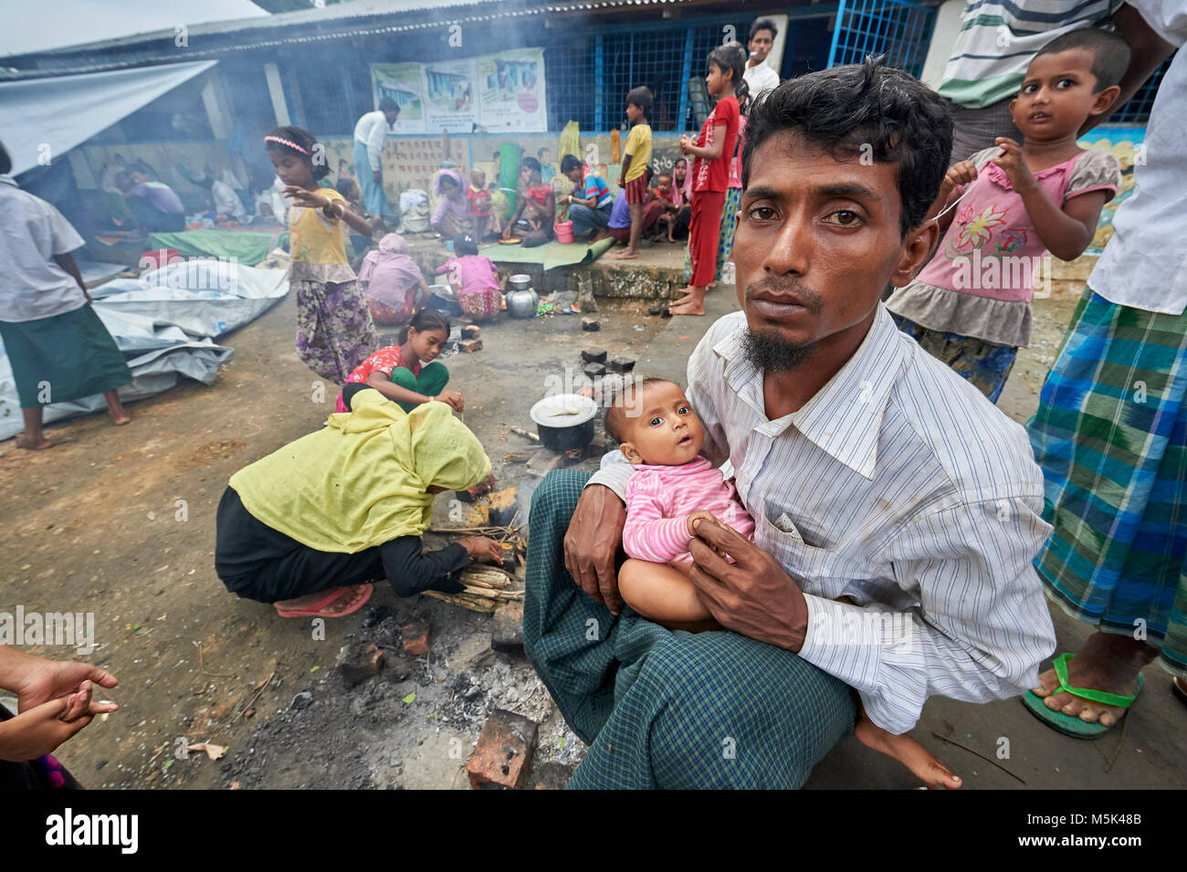 A Rohingya man who just crossed the border from Myanmar, waits with a child to complete registration in the Kutupalong Camp in Bangladesh. Stock Photo