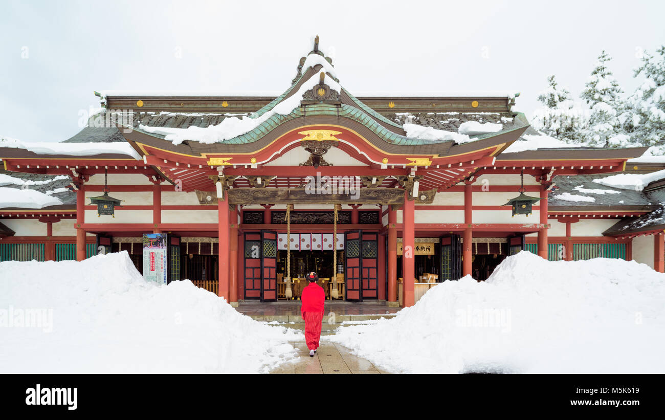 Japanese Woman in Red at Temple with Snow Stock Photo