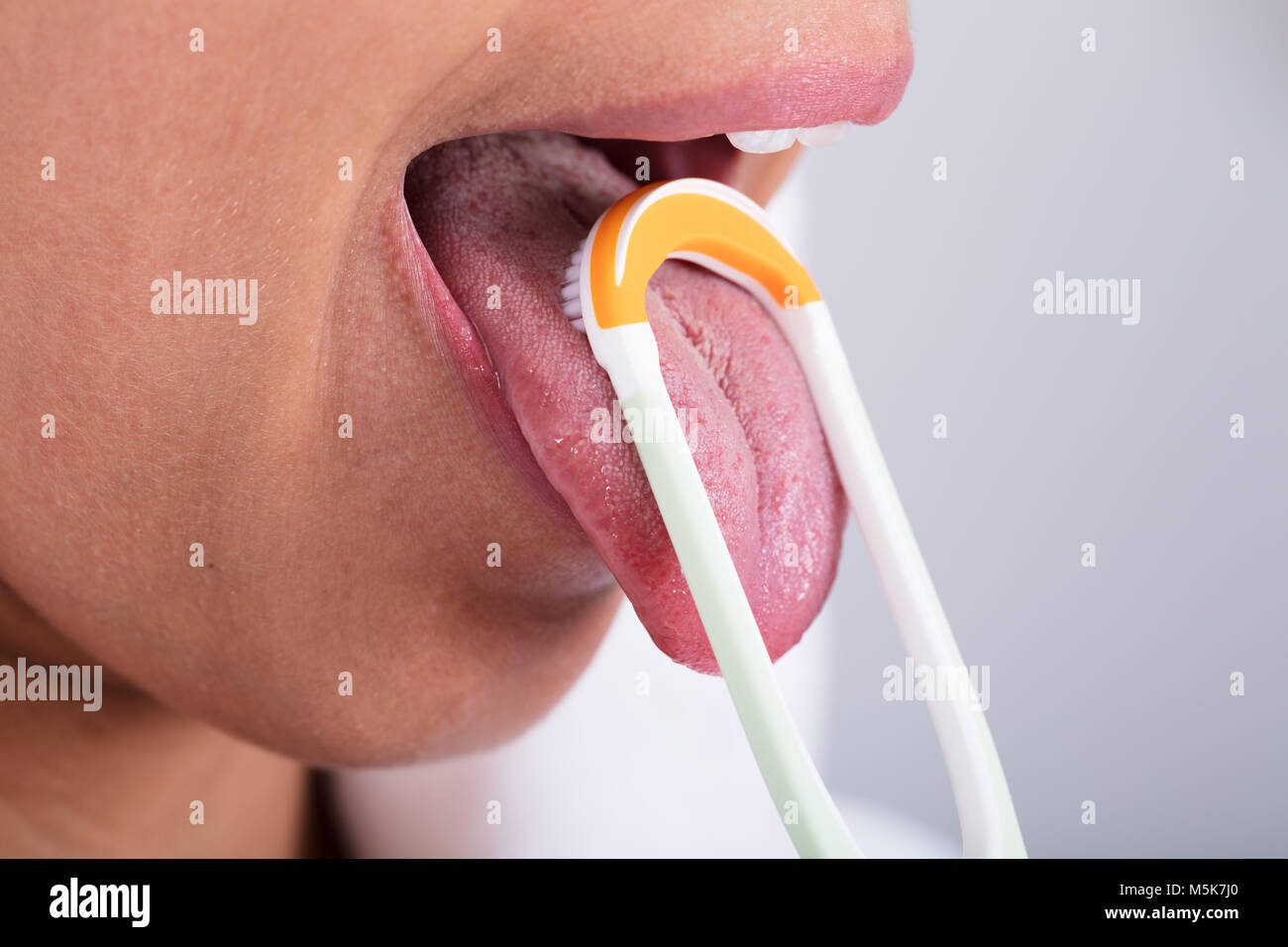 Photo Of Young Woman Cleaning Tongue With Cleaner Stock Photo
