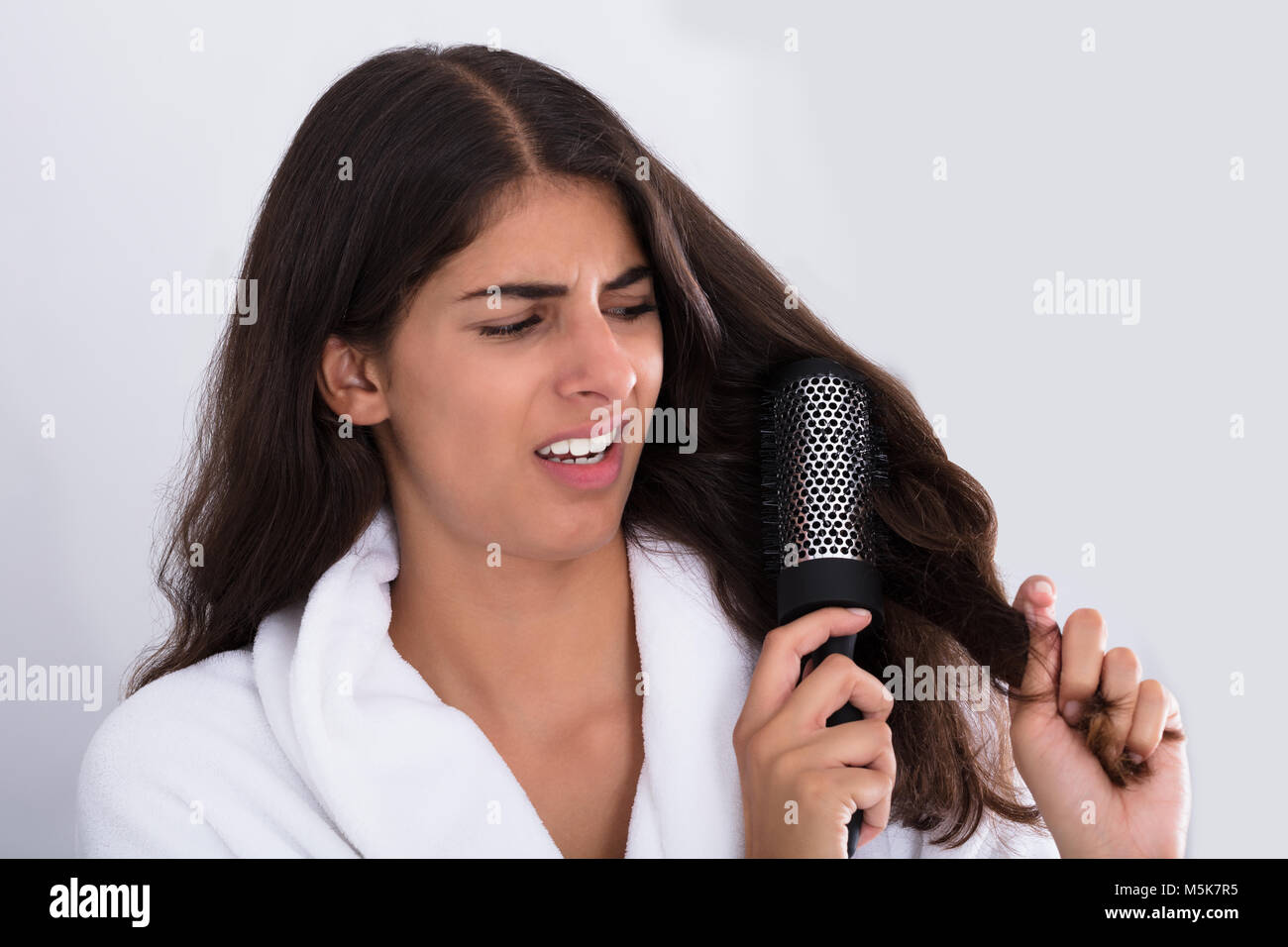 Beautiful Woman In Bathrobe Brushing Her Curly Hair At Home Stock Photo