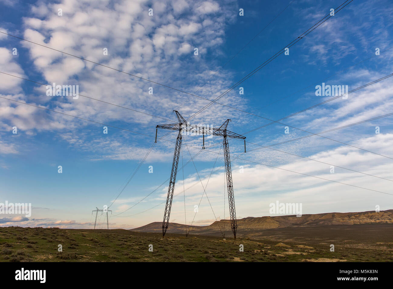 Power lines in a field against a blue sky with clouds Stock Photo - Alamy
