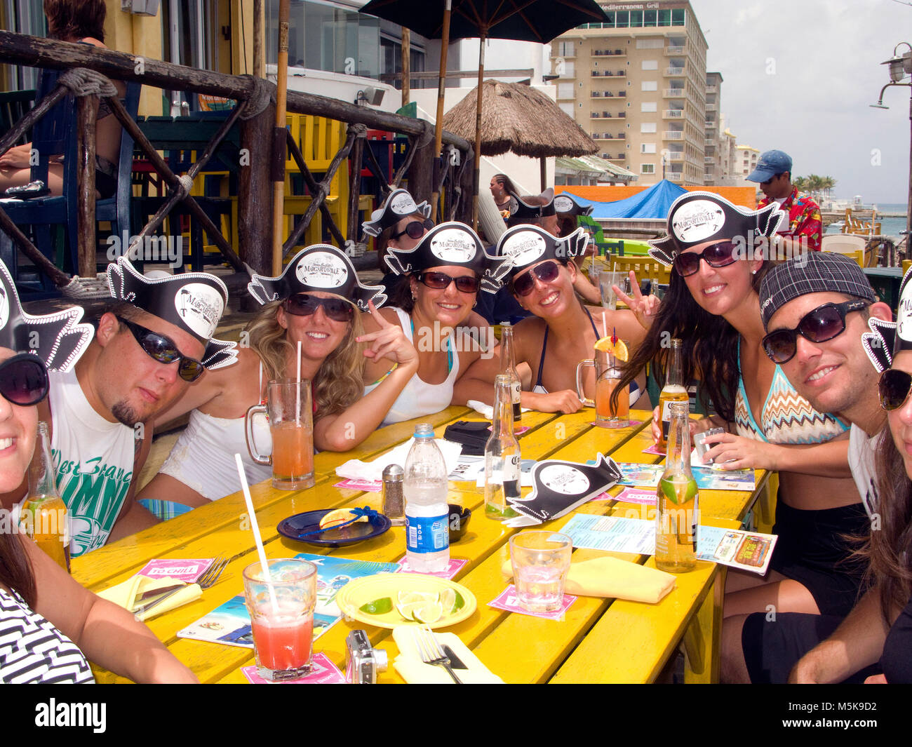 Young tourists with pirate caps celebrating at beach bar, divers bar Margaritaville, San Miguel, Cozumel, Mexico, Caribbean Stock Photo