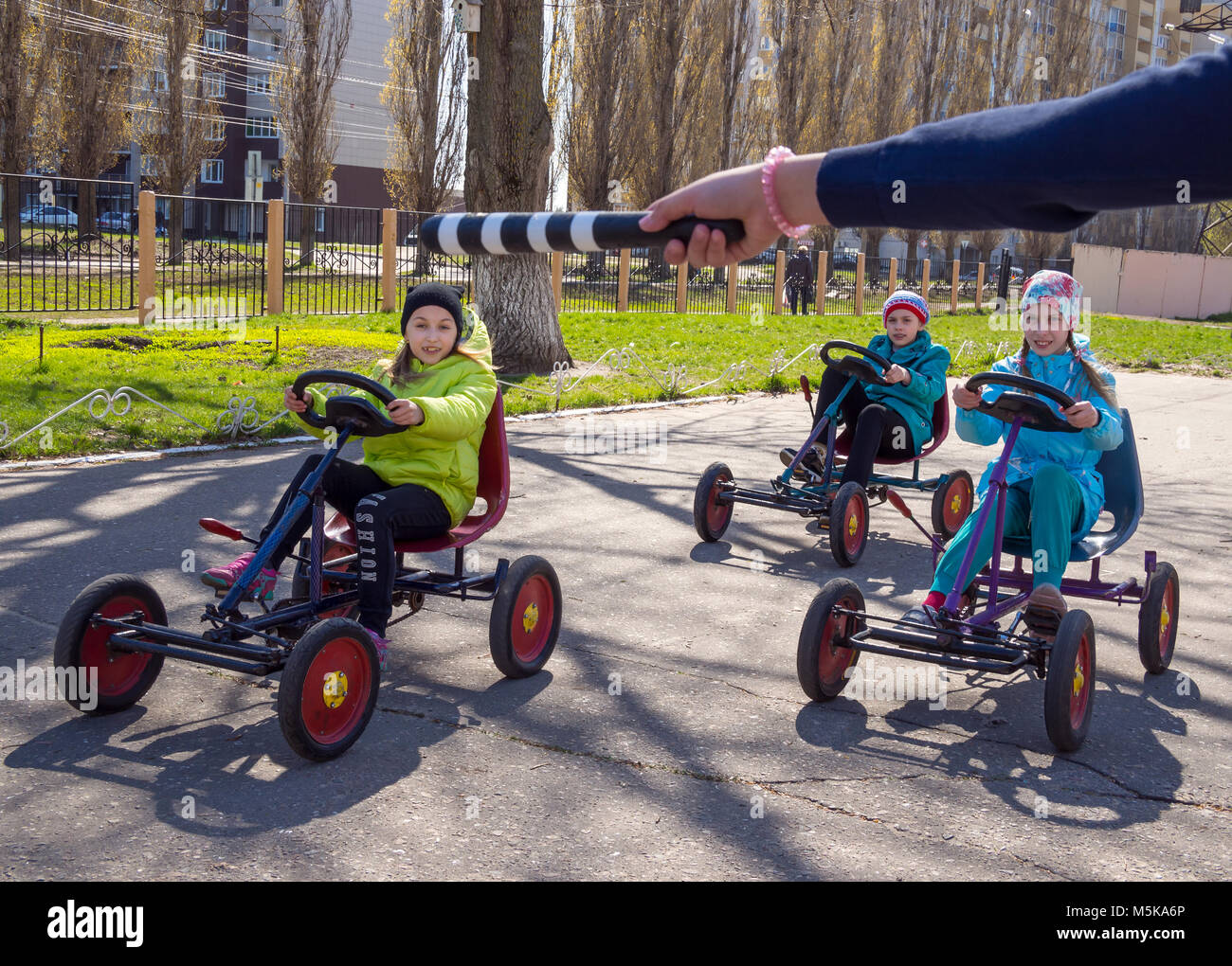 Voronezh, Russia - April 26, 2017: Children on toy cars execute commands of the regulator Stock Photo