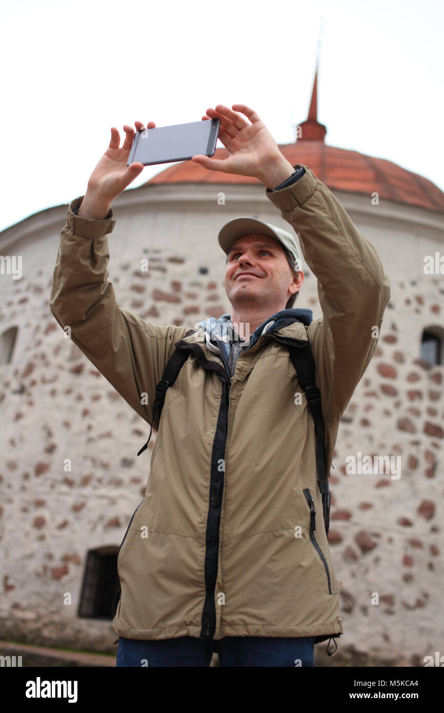 Tourist making selfie against the Round Tower in Vyborg, Russia Stock Photo