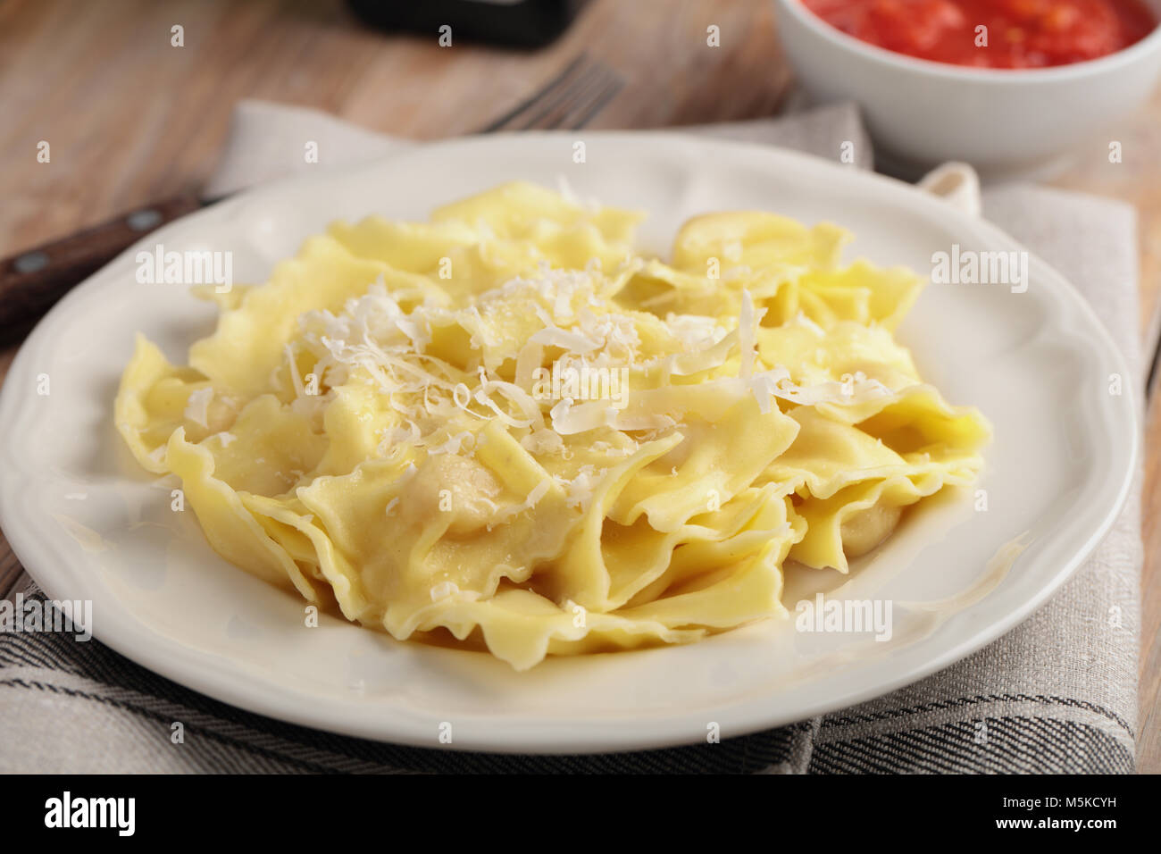 Italian ravioli with shredded Parmesan cheese and tomato sauce Stock Photo