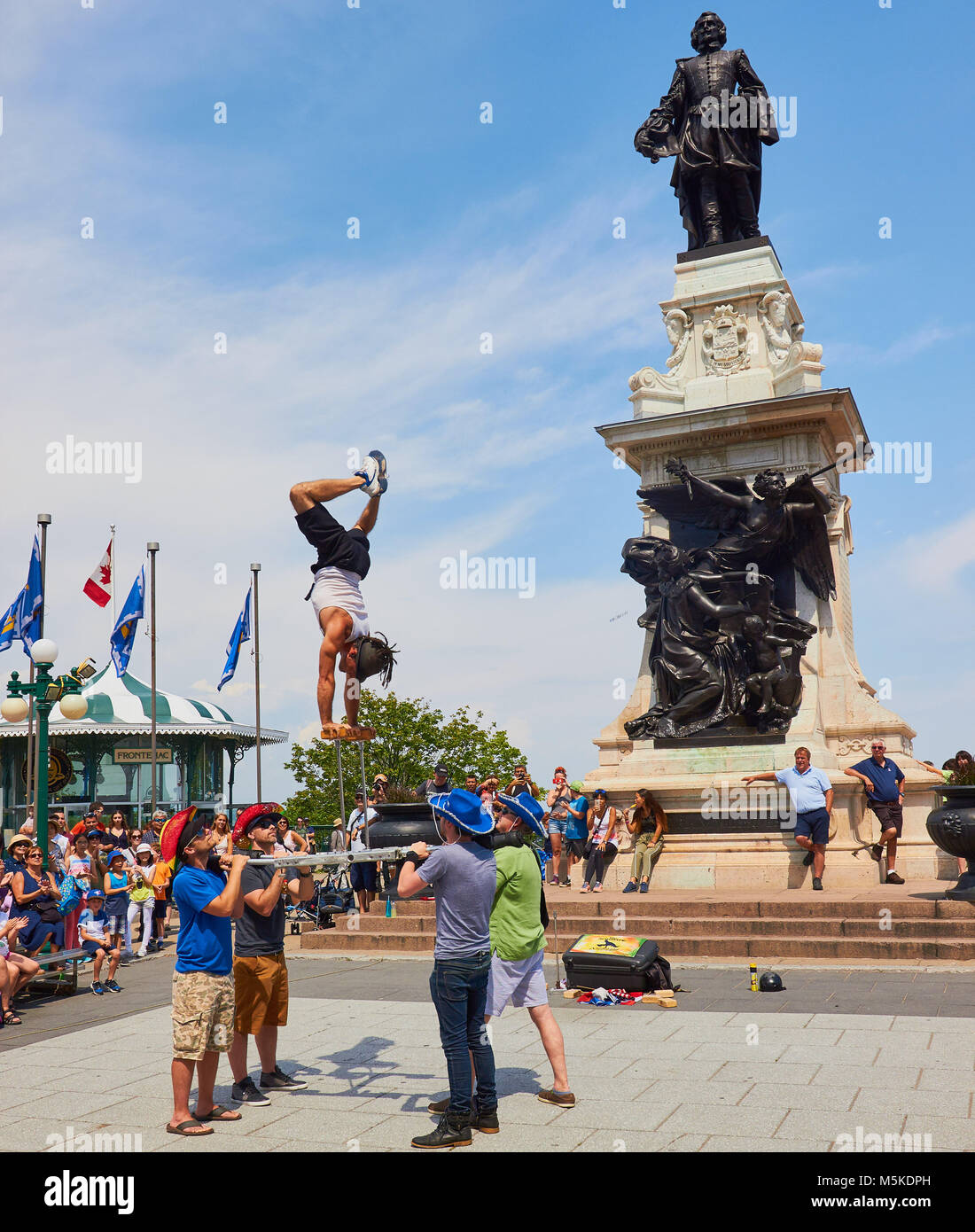 Street performer balancing on his hands and statue of Samuel de Champlain, Terrasse Dufferin (1879), Quebec City, Quebec Province, Canada. Stock Photo