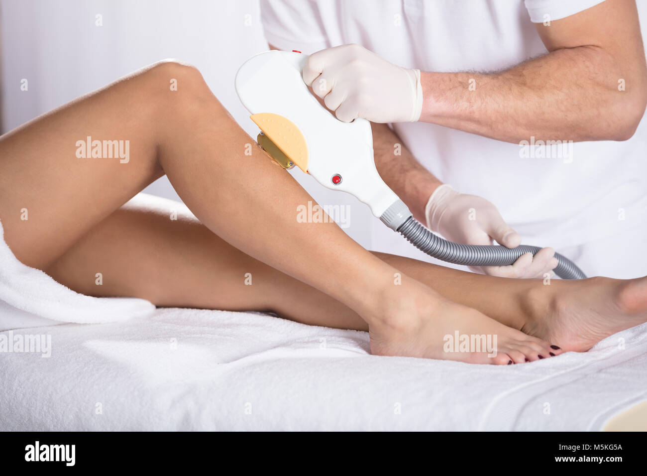 Low Section Of Young Woman Getting Laser Treatment On Leg At Spa Stock Photo
