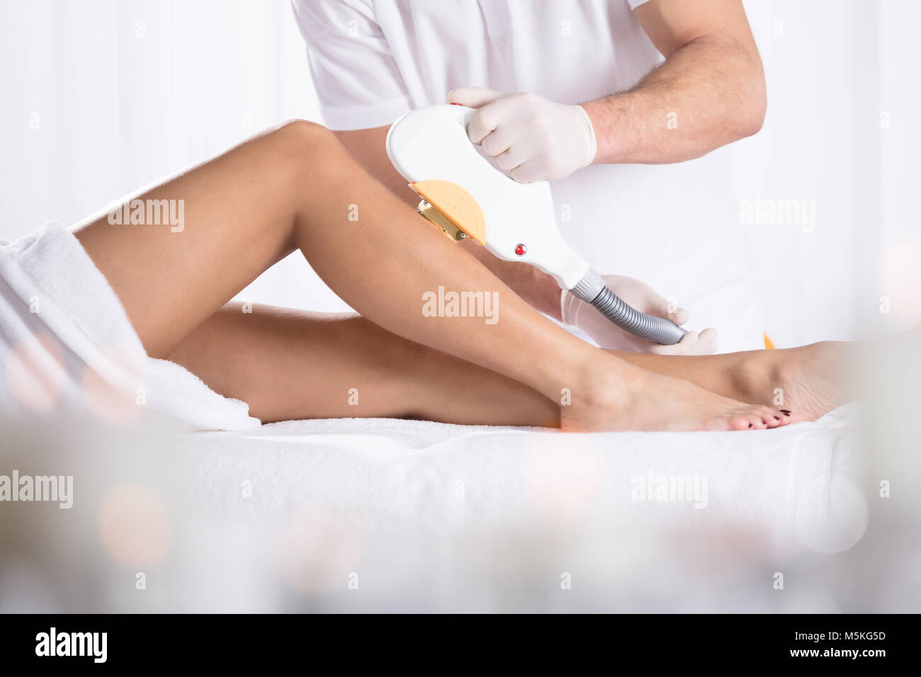 Low Section Of Young Woman Getting Laser Treatment On Leg At Spa Stock Photo