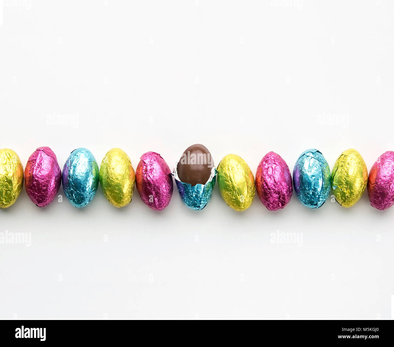 Foil wrapped easter candy in a row one candy unwrapped Stock Photo