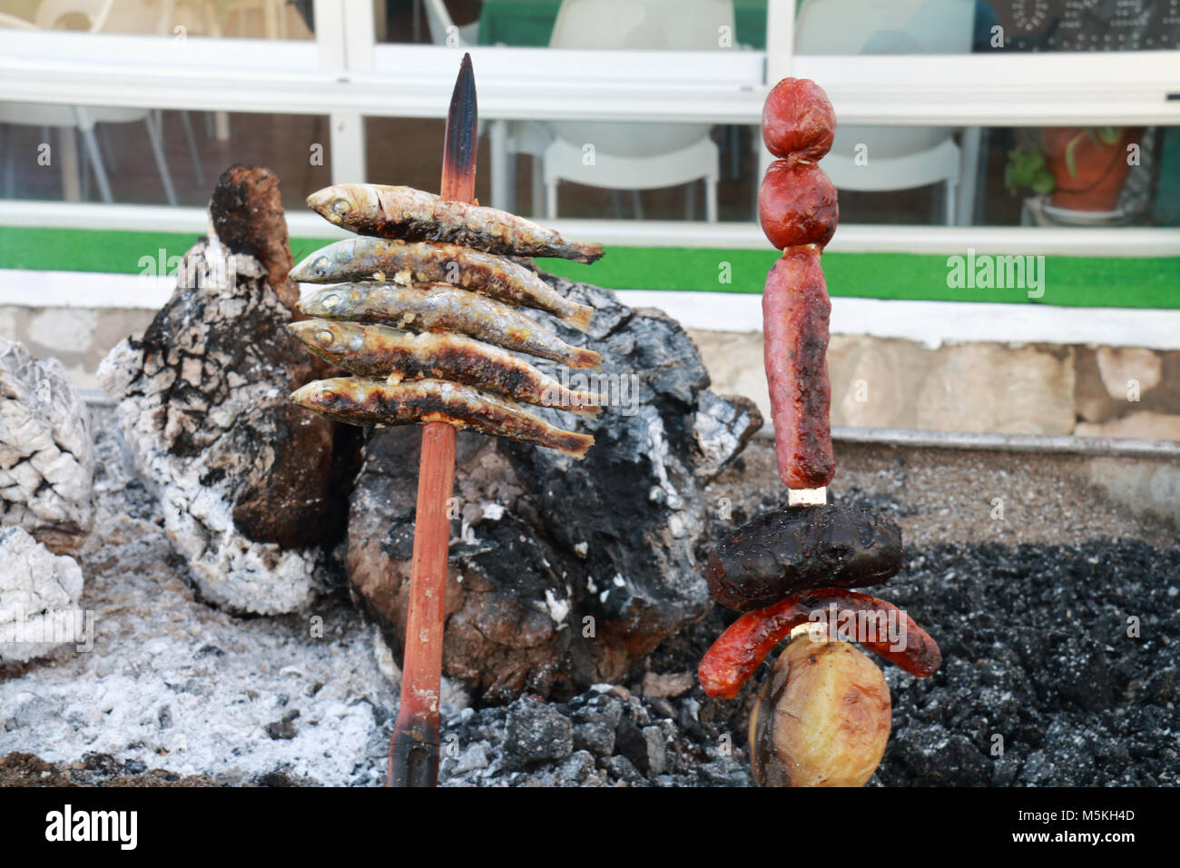 Skewer of sardines roasting in the embers of firewood, typical food of the coasts of Andalusia, to the south of Spain Stock Photo