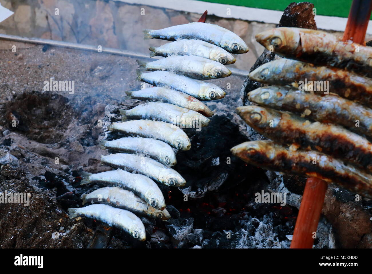 Skewer of sardines roasting in the embers of firewood, typical food of the coasts of Andalusia, to the south of Spain Stock Photo