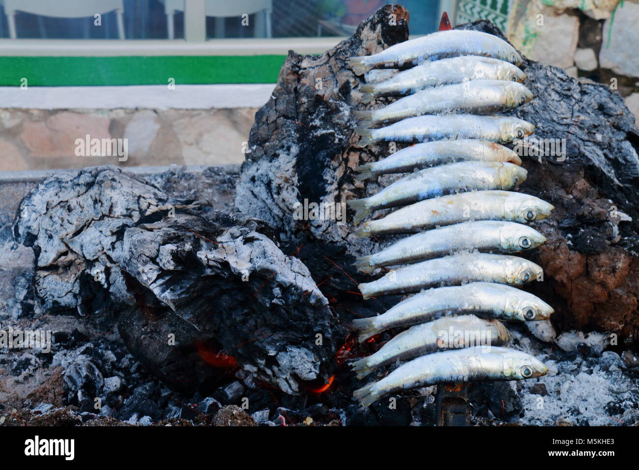 Skewer of sardines roasting in the embers of firewood, typical food of the coasts of Andalusia, to the south of Spain Stock Photo