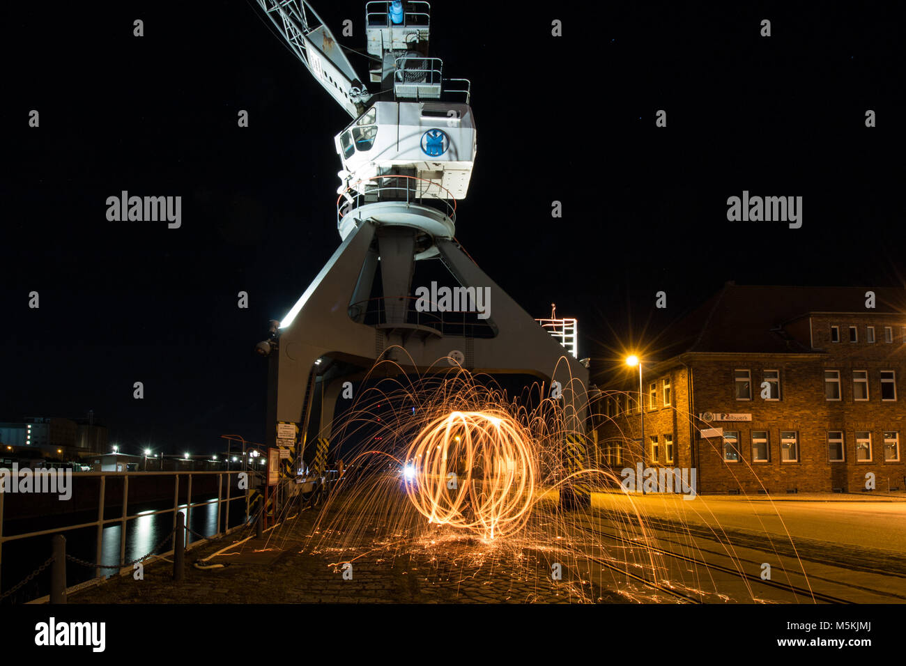 Old loading crane with fireball. Steel wool. At an old dock Stock Photo Alamy
