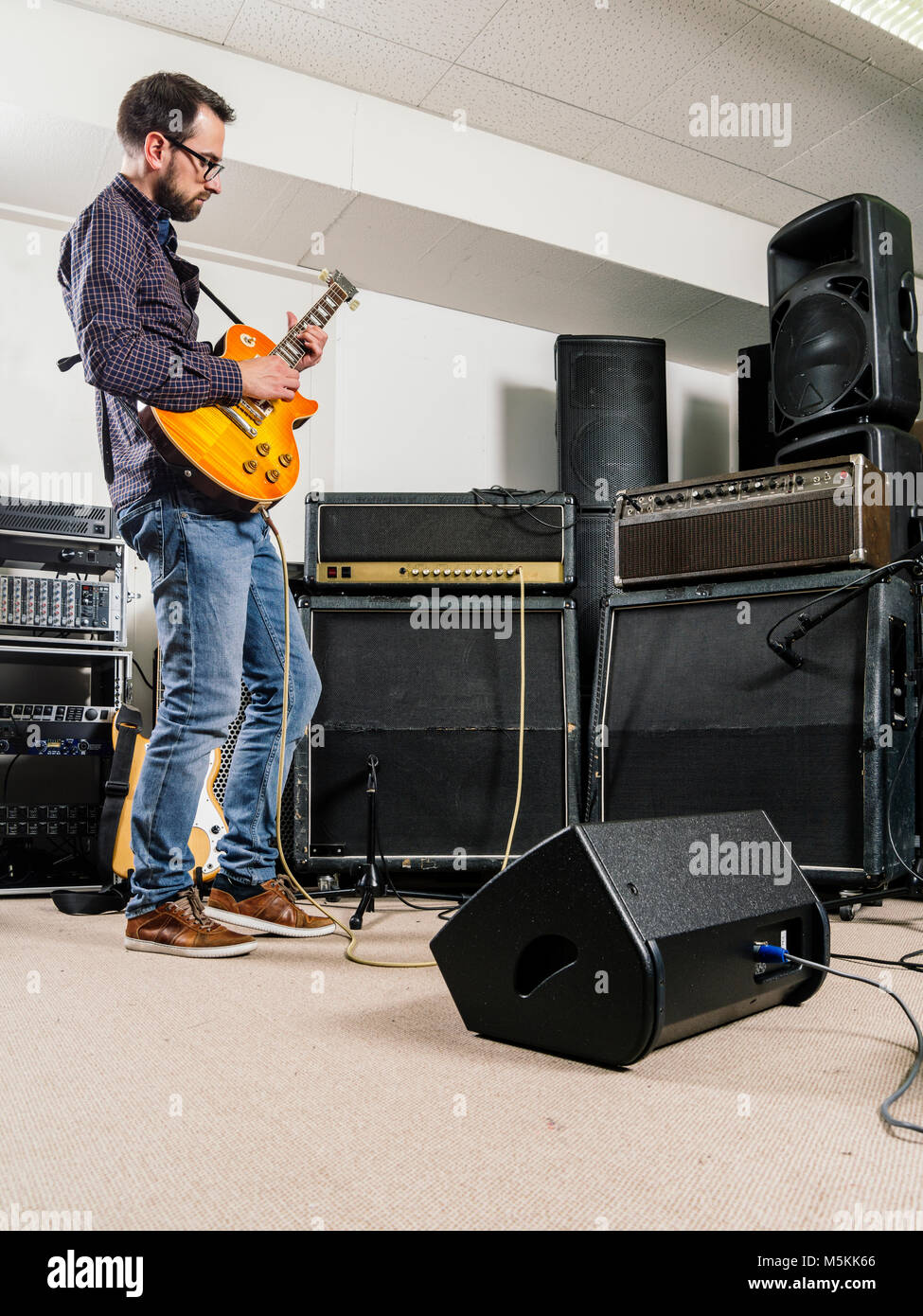 Photo of a man playing his electric guitar in a recording studio in