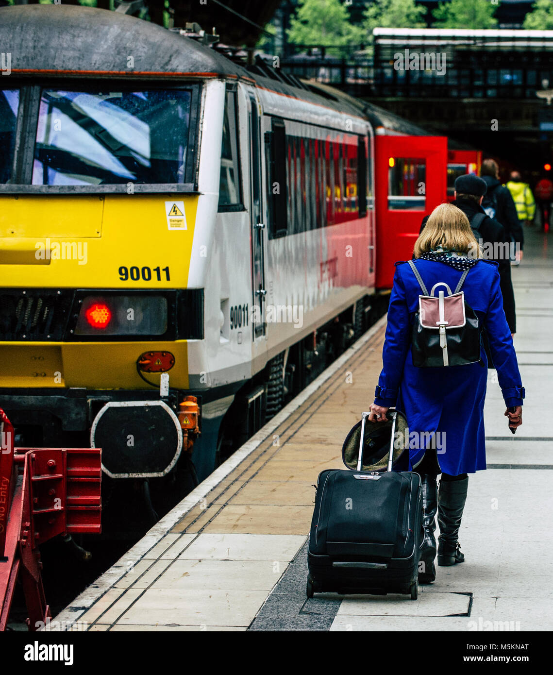 A woman walks along the platform in Liverpool Street Station to catch a train out of London Stock Photo