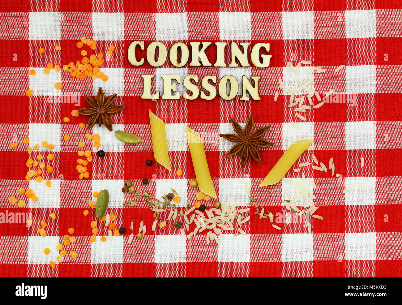 Cooking lesson written with wooden letters on checkered cloth and cooking ingredients Stock Photo