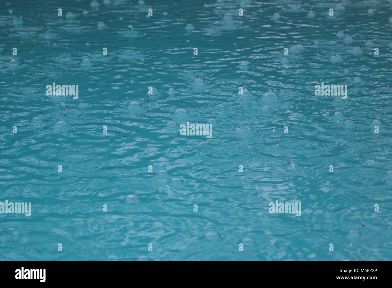 Rain in pool causing bubbles and circles Stock Photo Alamy