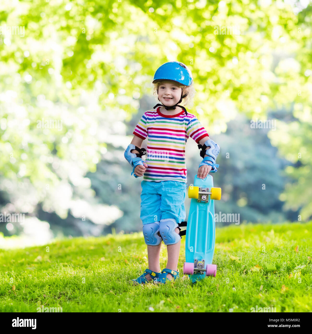 Child riding skateboard in summer park. Little boy learning to ride ...