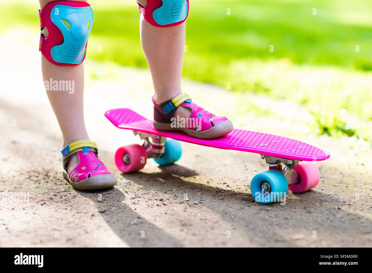 Child riding skateboard in summer park. Little girl learning to ride ...