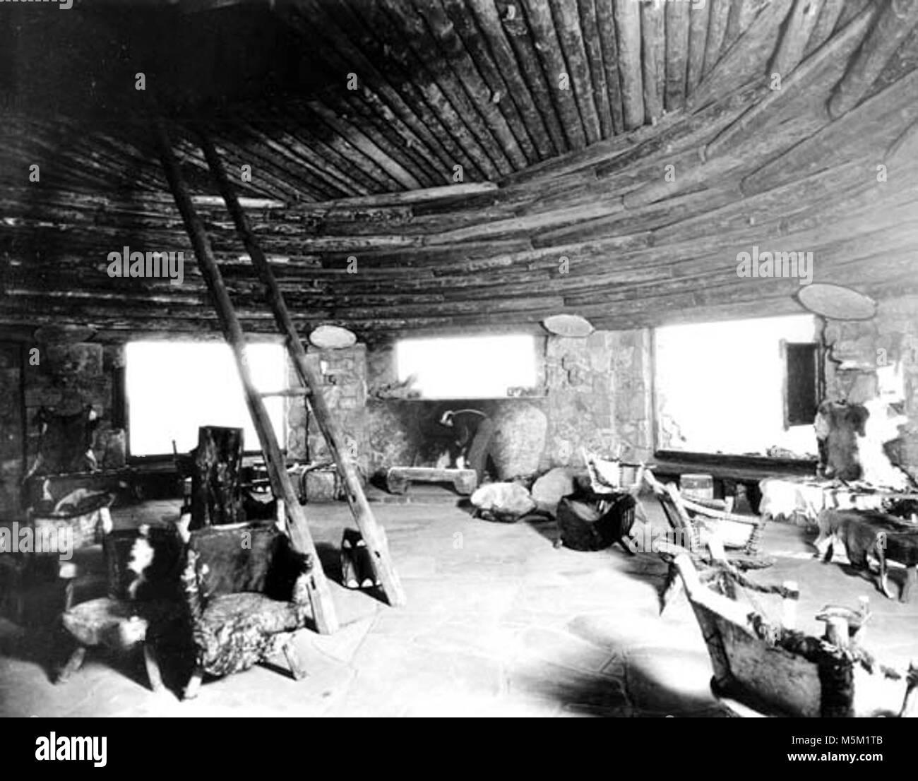 Grand Canyon Historic- Desert View Watchtower Interior c . INTERIOR  DESERT VIEW  WATCHTOWER KIVA ROOM. MARY COLTER DECOR. NATIVE EMPLOYEE BY  FIREPLACE.TIMBERS SALVAGED FROM GRANDVIEW HOTEL. GRCA 15934 CIRCA 1932. FRED HARVEY CO. Stock Photo