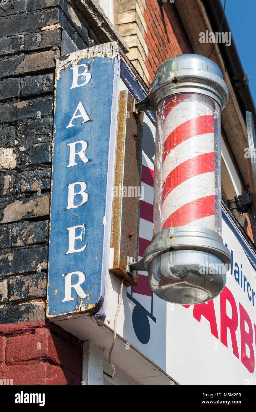 Traditional red and white barbers pole outside men's hairdressers Stock Photo