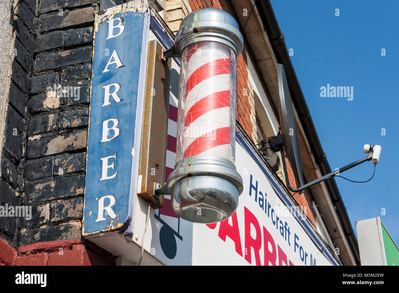 Traditional red and white barbers pole outside men's hairdressers Stock Photo