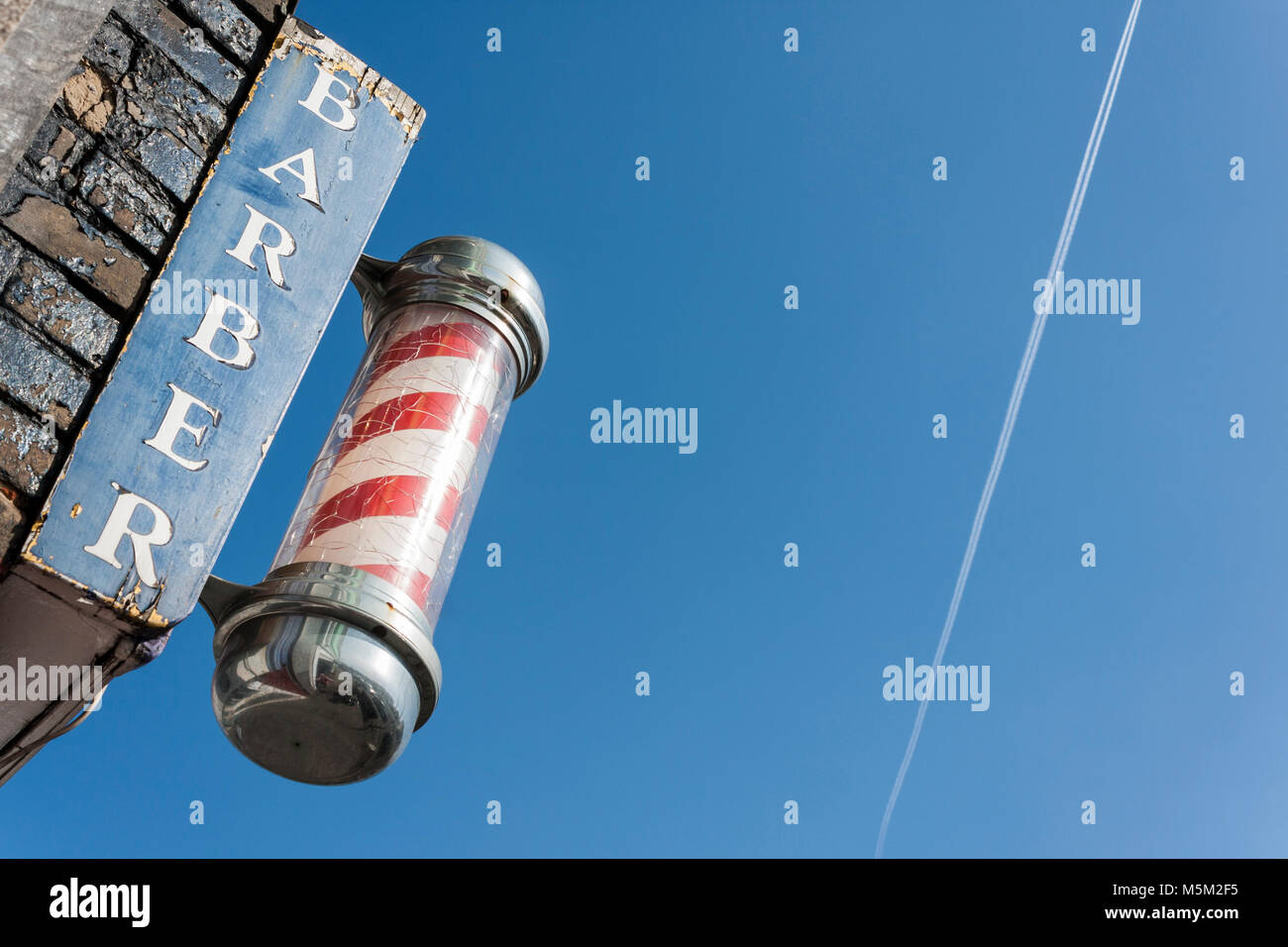 Traditional red and white barbers pole outside men's hairdressers Stock Photo
