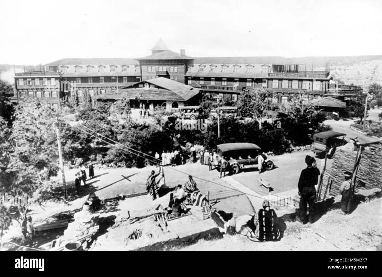 Grand Canyon Historic El Tovar Hotel . EL TOVAR AS SEEN FROM THE ROOF OF HOPI HOUSE.  NATIVE EMPLOYEES POSING ON DIFFERENT LEVELS OF ROOF. FRED HARVEY TOURING CARS PARKED AROUND ENTRANCE LOOP. CIRCA 1922. FRED HARVEY Stock Photo