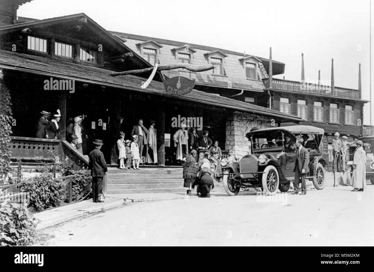 A Grand Canyon Historic El Tovar Hotel . VISITORS STANDING AROUND THE FRONT ENTRANCE  TO THE EL TOVAR HOTEL. HOPI DEMONSTRATORS POSING. TOUR AUTOMOBILE. CIRCA 1922. FRED HARVEY Stock Photo