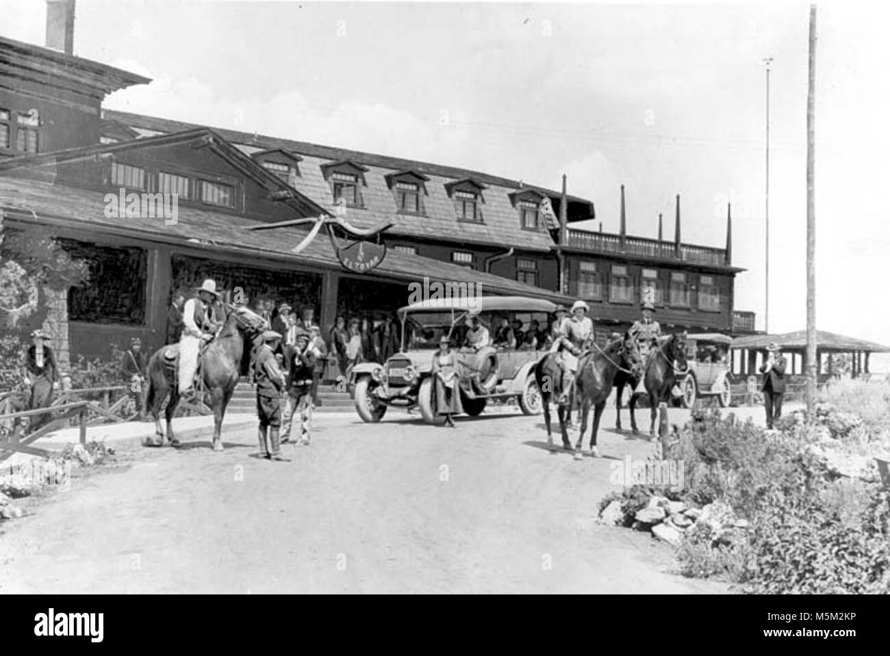 B Grand Canyon Historic El Tovar Hotel . VARIETY OF VISITORS & HORSES BY FRONT ENTRANCE TO EL TOVAR HOTEL. TOURING CARS. CIRCA 1922. FRED HARVEY Stock Photo