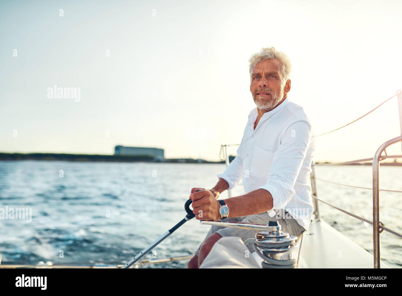 Mature man sitting alone on the deck of his yacht sailing on the open ...