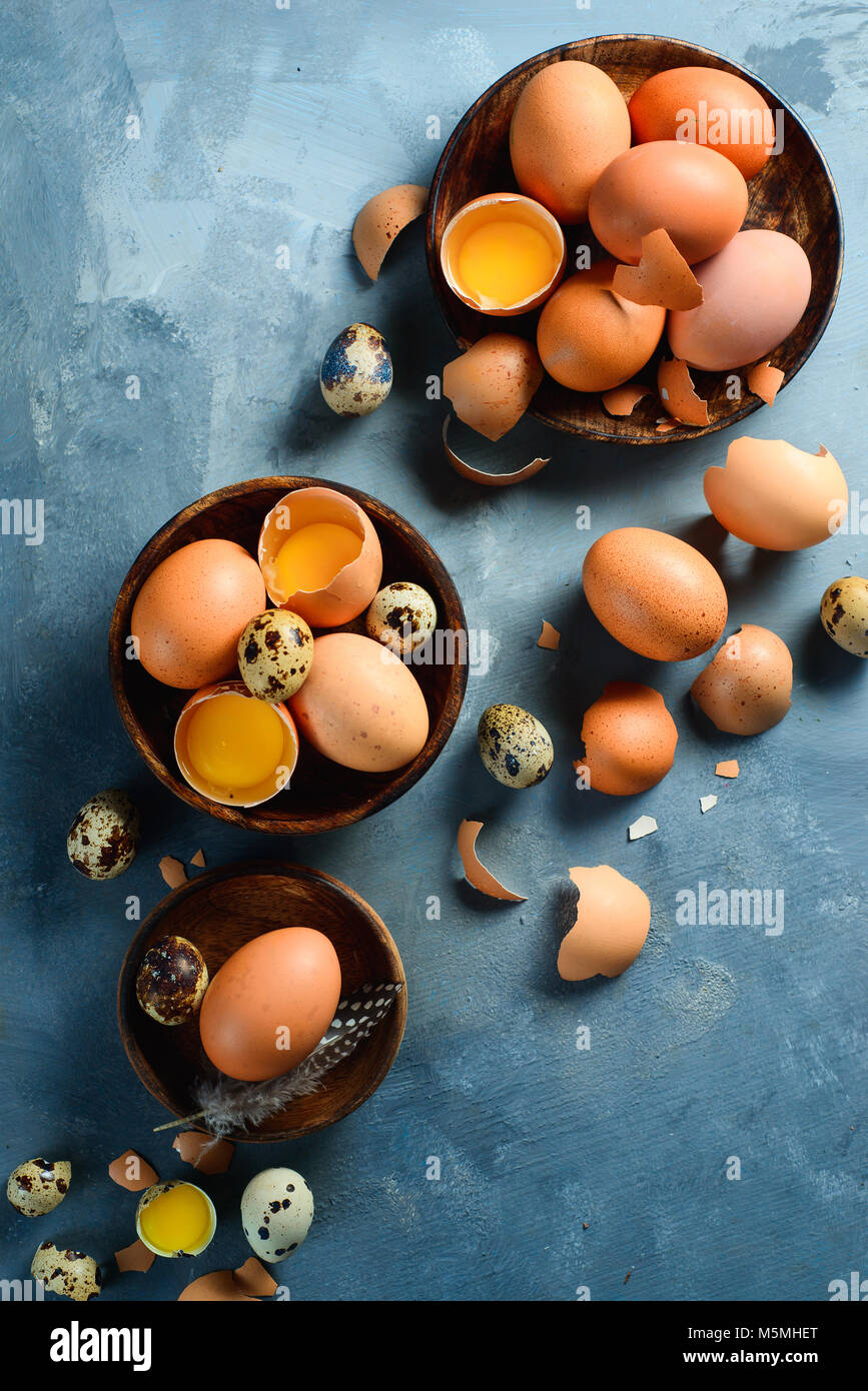 Raw eggs in wooden dishes flat lay. Cooking with fresh ingredients concept. Brown eggs on a concrete background with copy space. Stock Photo