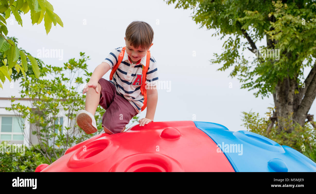 kid boy and backpack having fun to play on children's climbing toy at ...
