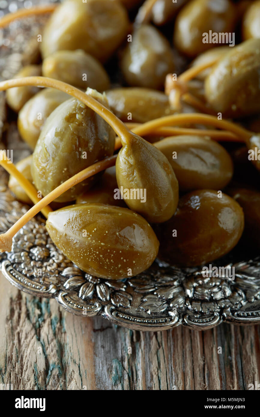Pickled caper berries in metal dish . Edible fruits of Capparis
