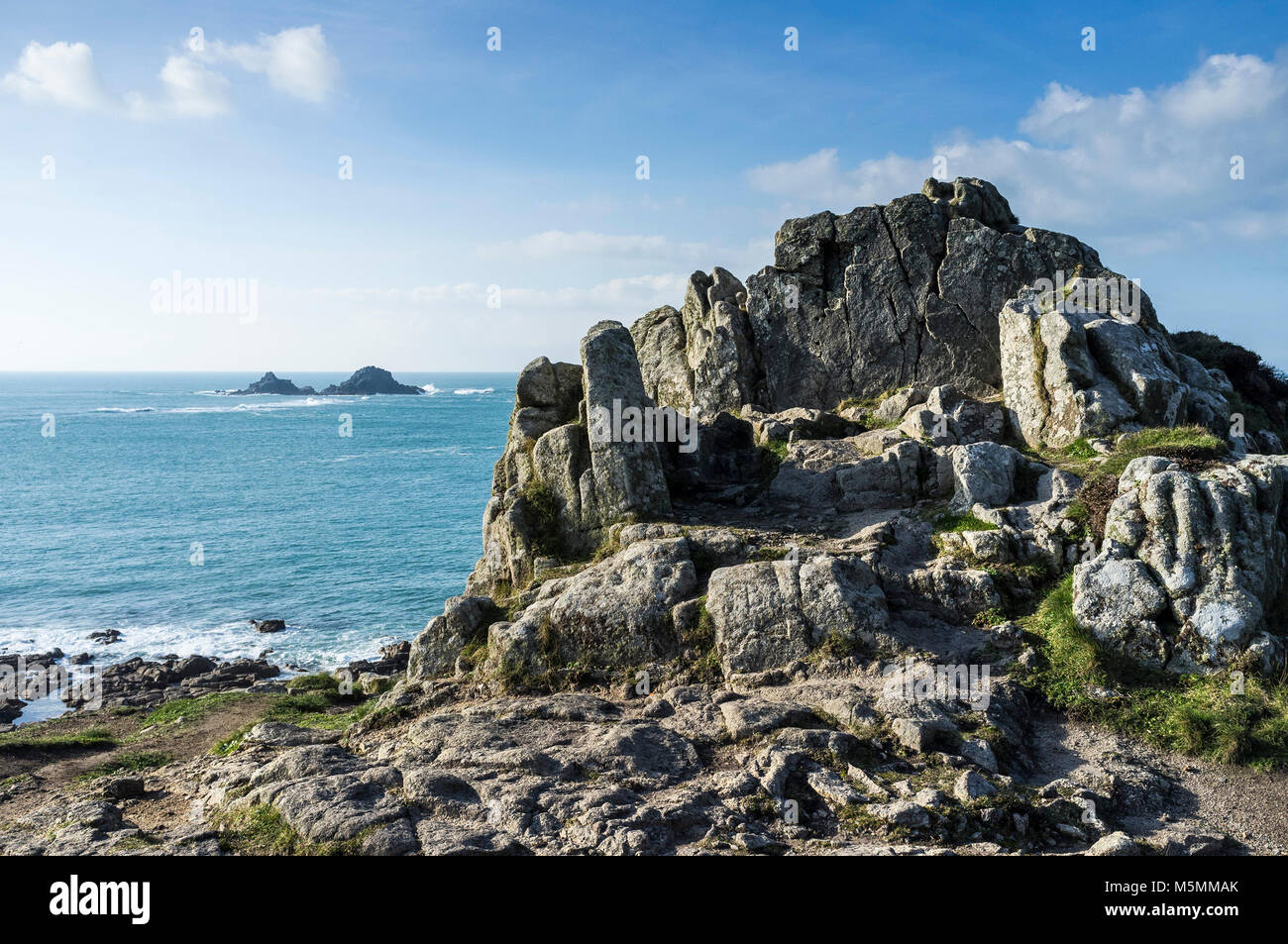 An outcrop of granite rock on the coast with the Brisons in the background  Cornwall. Stock Photo