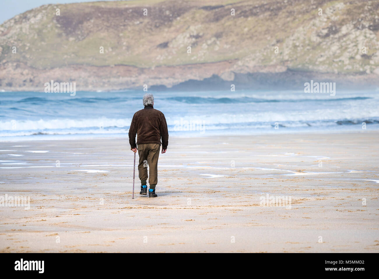 A mature man walking across the beach at Sennen Cove in Cornwall. Stock Photo