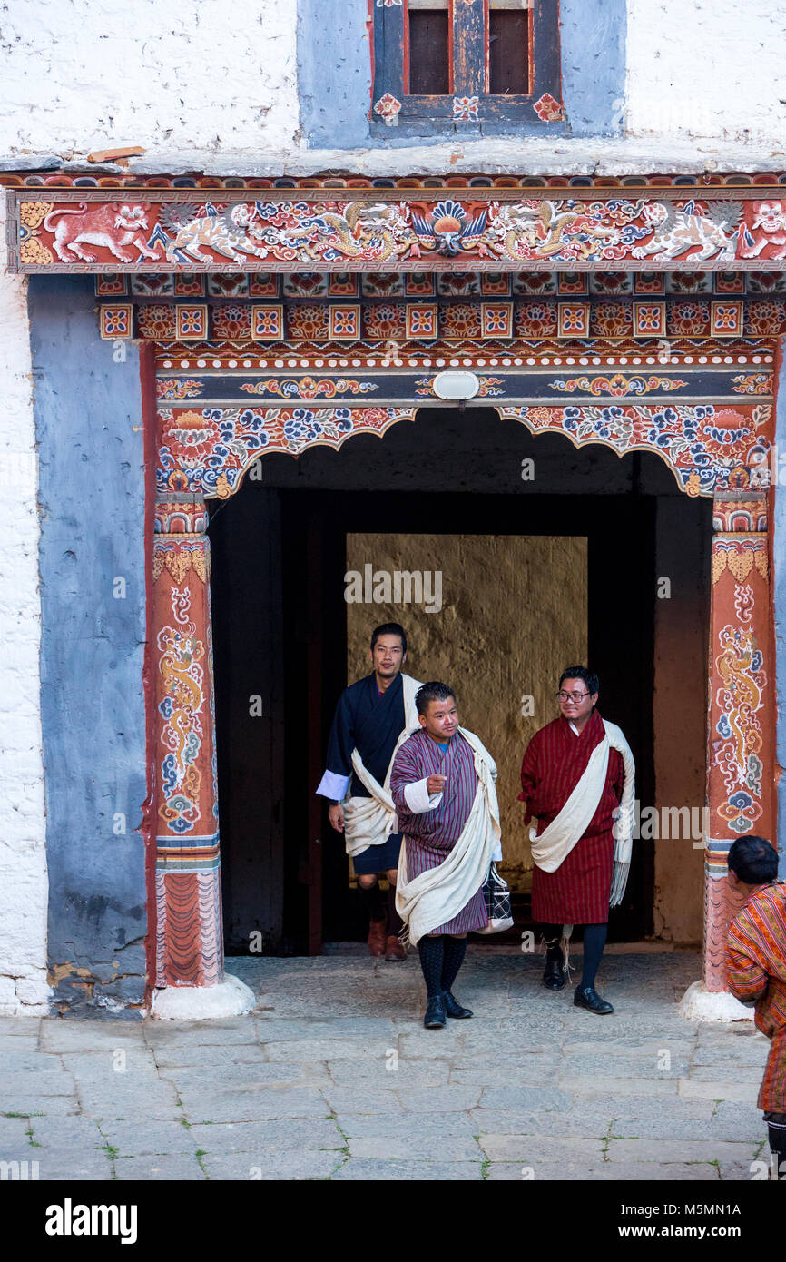 Trongsa, Bhutan.  Entryway into First Courtyard of The Trongsa Dzong (Monastery-Fortress), Viewed from Inside the Court.  Men Wearing Gho, the Traditi Stock Photo