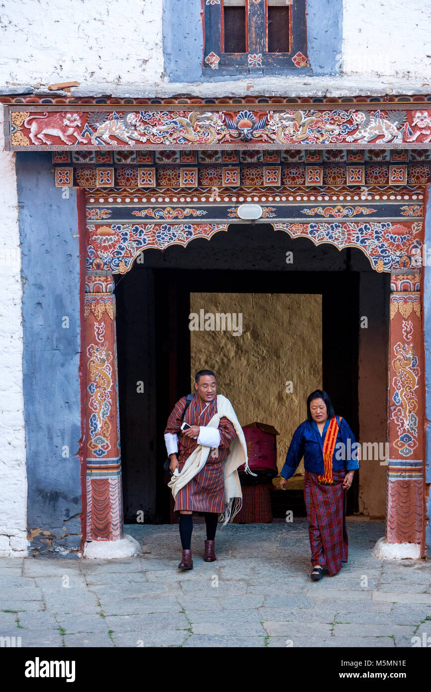 Trongsa, Bhutan.  Man and Woman Passing through Entryway into First Courtyard of The Trongsa Dzong (Monastery-Fortress), Viewed from Inside the Court. Stock Photo