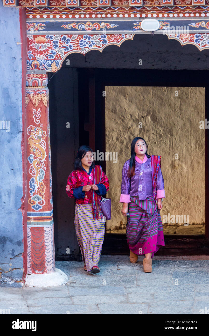 Trongsa, Bhutan.  Two Women in Traditional Dress Entering First Courtyard of The Trongsa Dzong (Monastery-Fortress), Viewed from Inside the Court. Stock Photo
