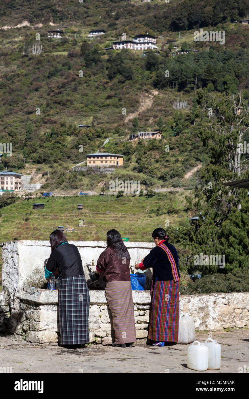 Trongsa, Bhutan.  Bhutanese Women Filling Water Jugs at the Water Tap in The Trongsa Dzong (Monastery-Fortress). Stock Photo
