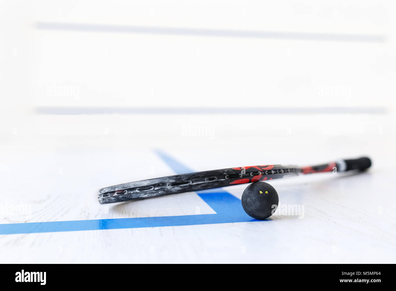 squash racket and ball on the wooden floor. Racquetball equipment on