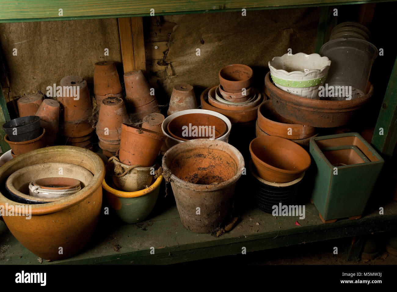 Old terracotta planting pots hidden under table in garden shed Stock Photo