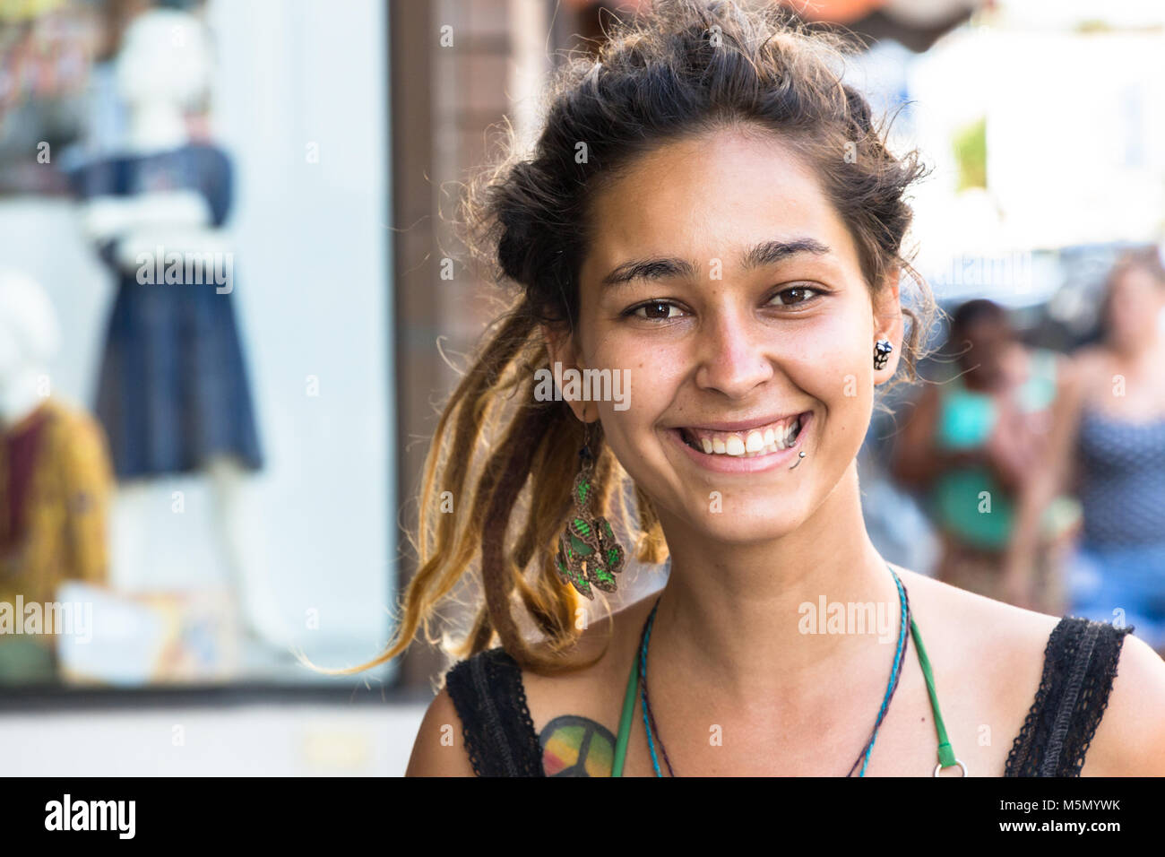 Itajai, Santa Catarina, Brazil - February 22th, 2018: A female brazilian street bracelets vendor, with tattoo and piercing in her face smiling at street. Stock Photo
