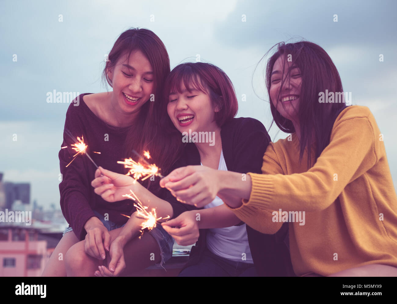 Happy group of asia girl friends enjoy and play sparkler at roof top party at evening sunset,Holiday celebration festive,teenage lifestyle,freedom and Stock Photo