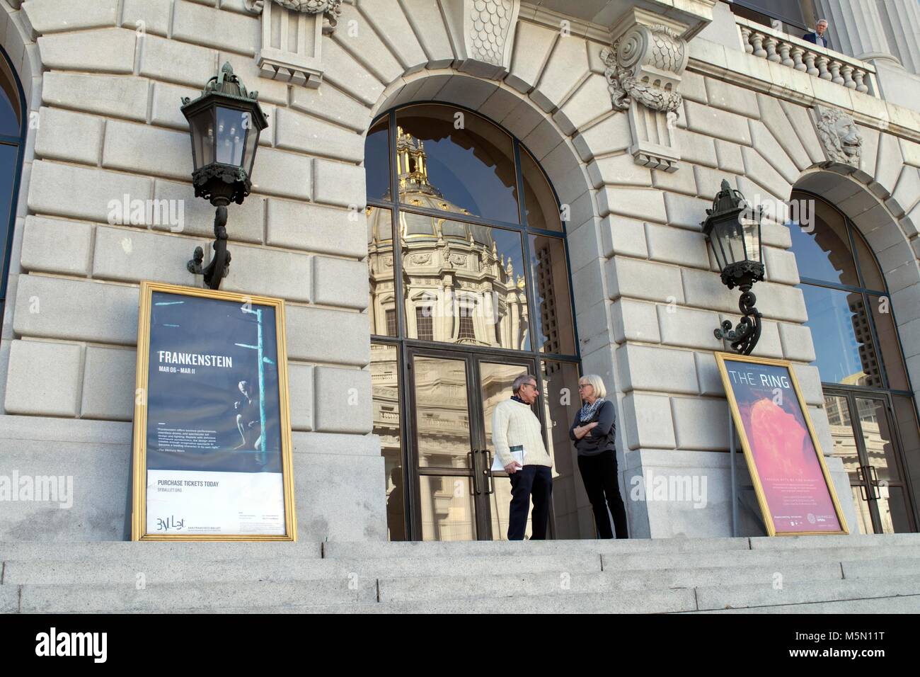 Two people chat in front of a window in San Francisco, near City Hall. Stock Photo