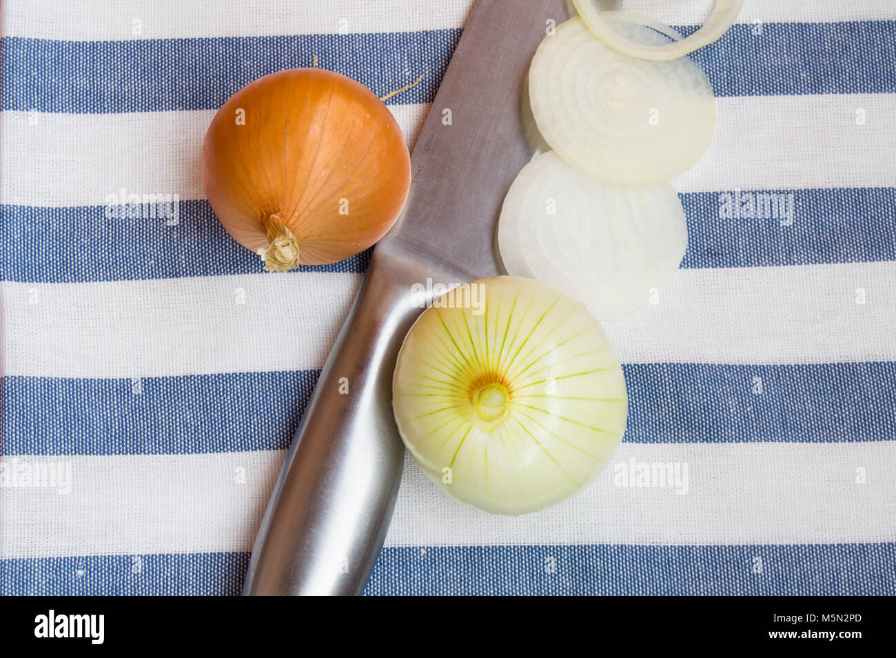 Bulb raw onion and a knife lying on striped cloth Stock Photo - Alamy