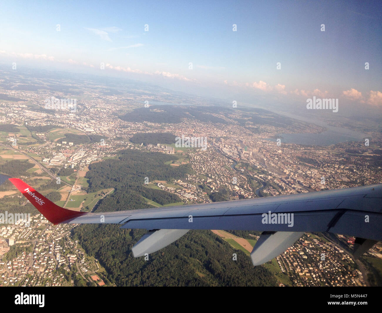 The wing of a Helvetic airways airplane above the city zurich in Switzerland Stock Photo