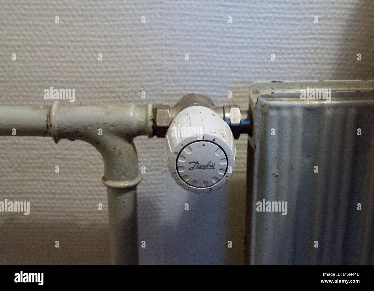 White analog Danfoss thermostat on an old radiator in Denmark Stock
